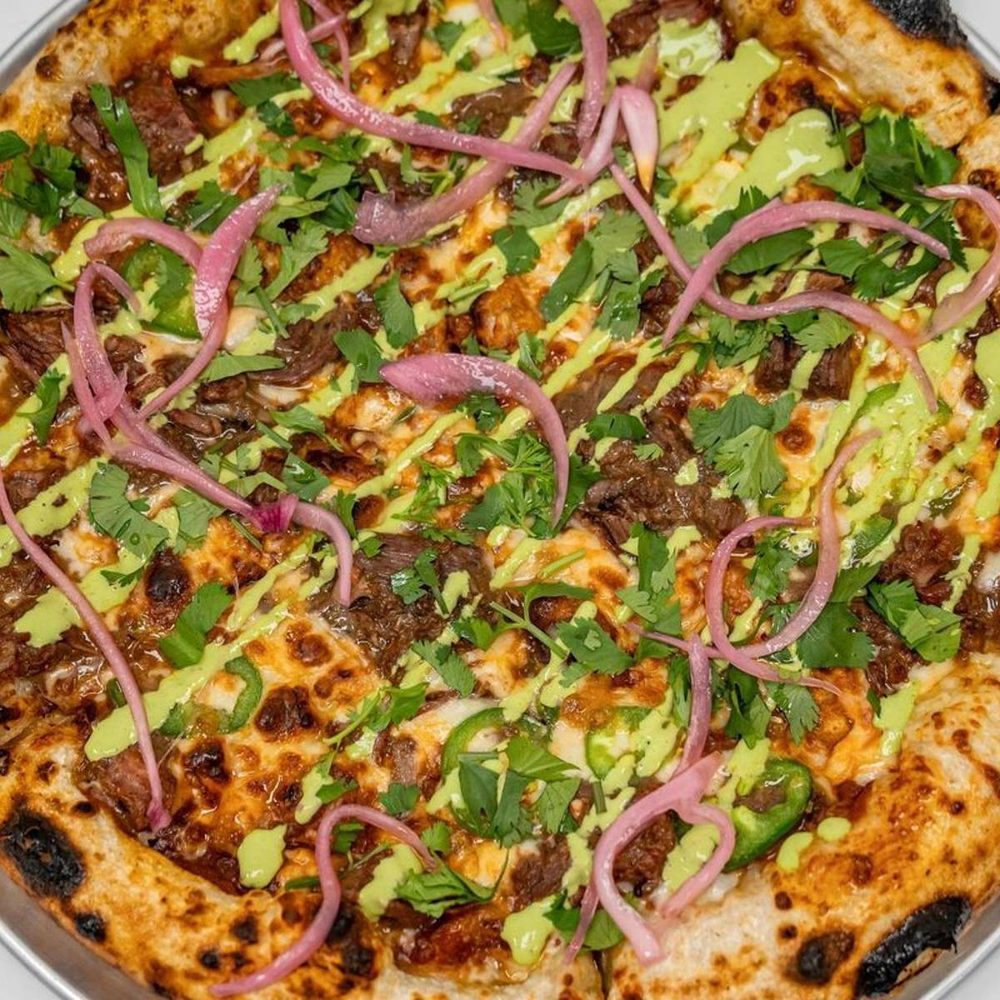 Birria-style beef pizza with cilantro, pickled onion and verde crema